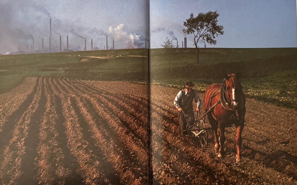 A farmer plowing near Cracow, with the steelworks of Nowa Huta in the background